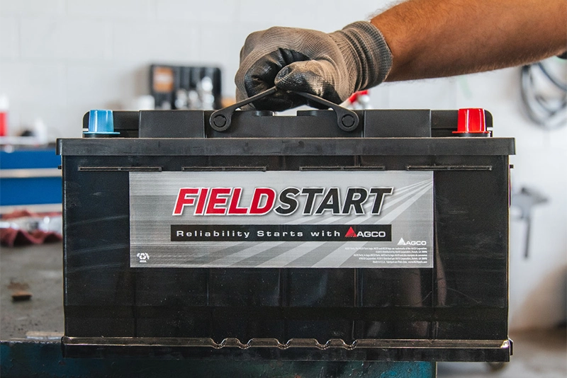 Buening Implement service technician holding field start battery from AGCO Parts.